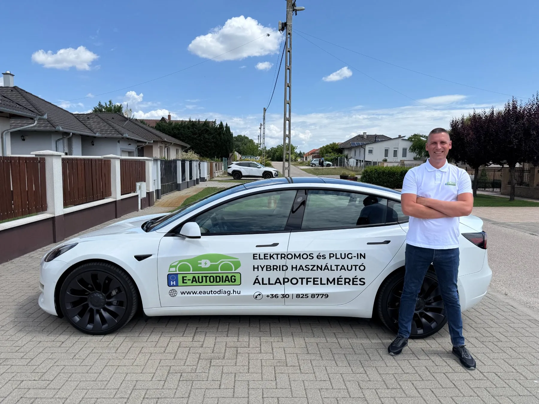 Kapás Krisztián az E-AUTODIAG feliratos fehér Tesla elektromos autó mellett